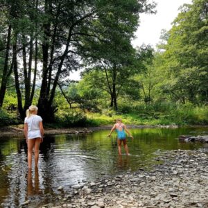 2 kinderen spelen aan de oever van een riviertje. Camping Vallee de l'Our.