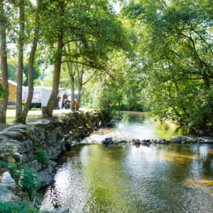 Een beek stroomt langs Camping Val d'Or. Aan de linker kant een safaritent.